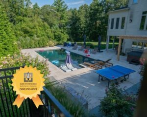 Aerial-style view of Hopkinton backyard pool and Walnut French Pattern Travertine patio designed by Elite Stoneworks with materials from Cornerstone Landscape Supplies.