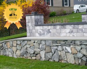 Photo of a retaining wall with natural stones with a seating wall on the top