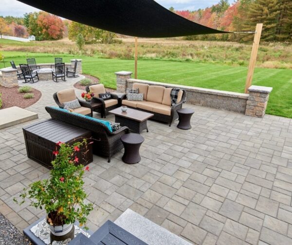 Spacious backyard patio with modular pavers, outdoor furniture, and built-in seating wall using the Andover Collection.