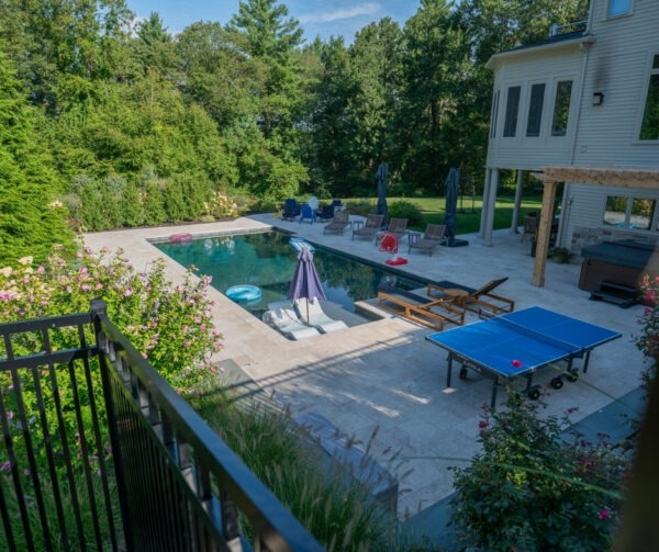 Aerial-style view of Hopkinton backyard pool and Walnut French Pattern Travertine patio designed by Elite Stoneworks with materials from Cornerstone Landscape Supplies.
